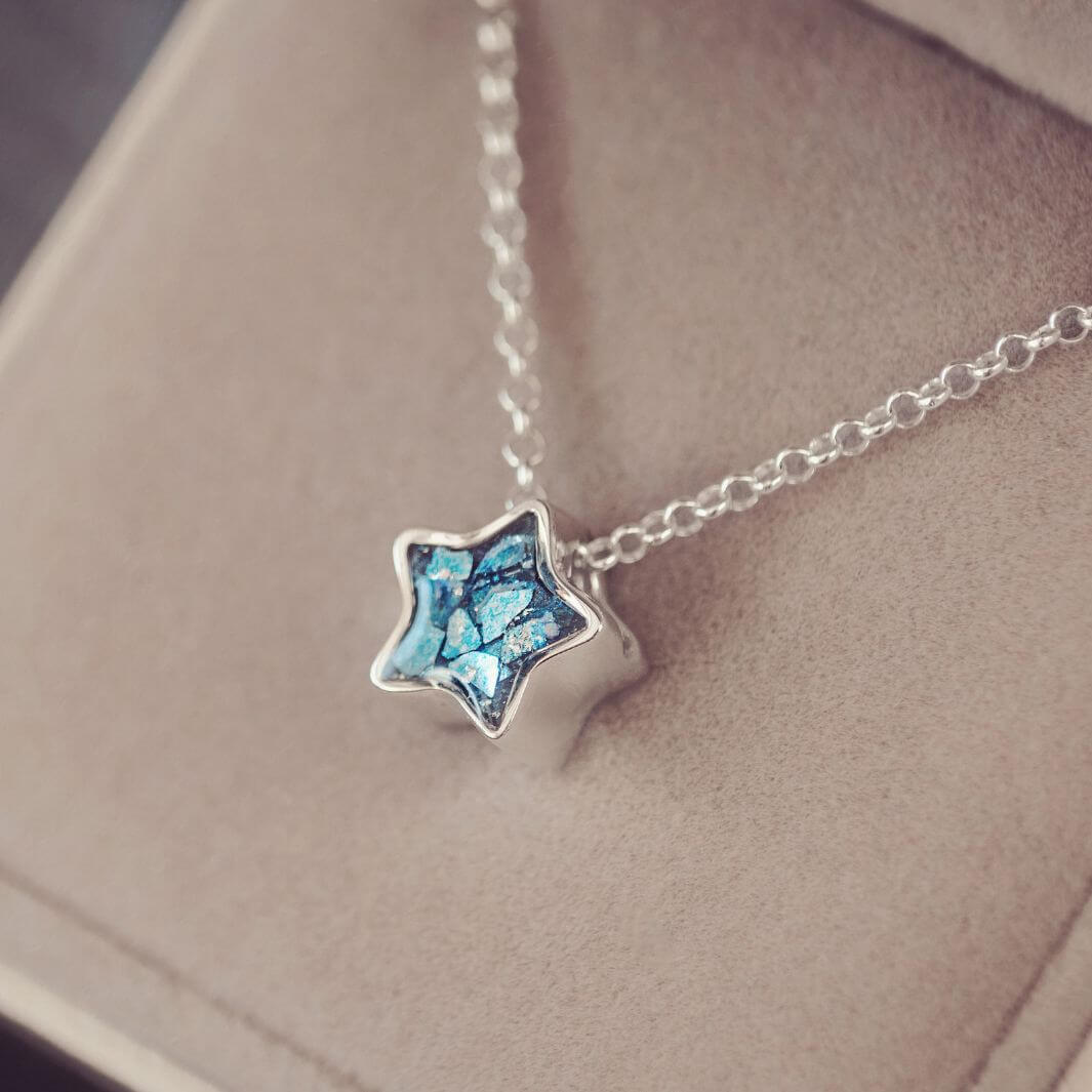 Star-shaped pendant necklace with blue gemstone on a soft surface