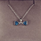 sterling silver bone shaped necklace, filled with cremation ashes, blue crystal and resin.