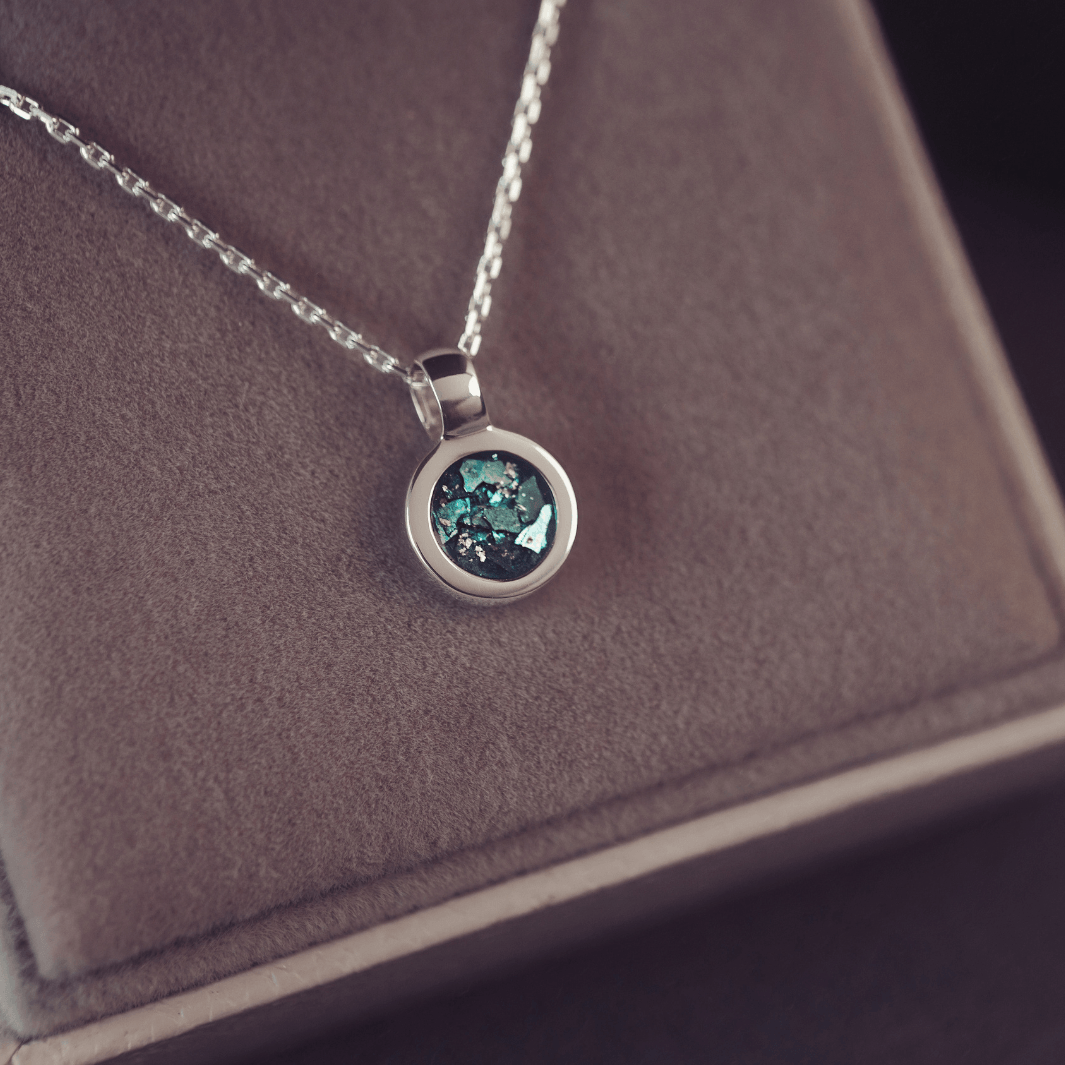 Silver necklace with a round pendant on a brown jewelry box