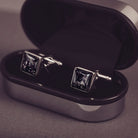 Square silver cufflinks containing cremation ashes, black crystal and resin sat in a black and silver cufflinks case 