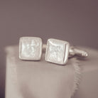 Square silver cufflinks containing cremation ashes, clear crystal and resin laying of beige fabric