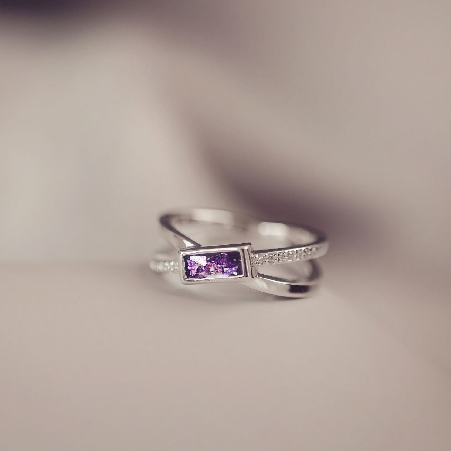 Silver ring with a purple gemstone on a blurred background