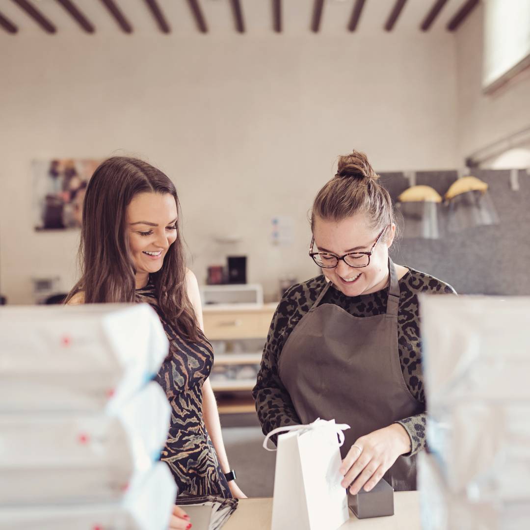 Two ladies standing in a workshop packing jewellery boxes