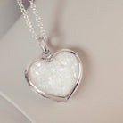 Sterling silver Large Heart necklace with a central section filled with memorial ashes and clear crushed crystals, displayed on a pale pink background.