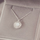 Silver necklace with a round pendant on a soft gray background