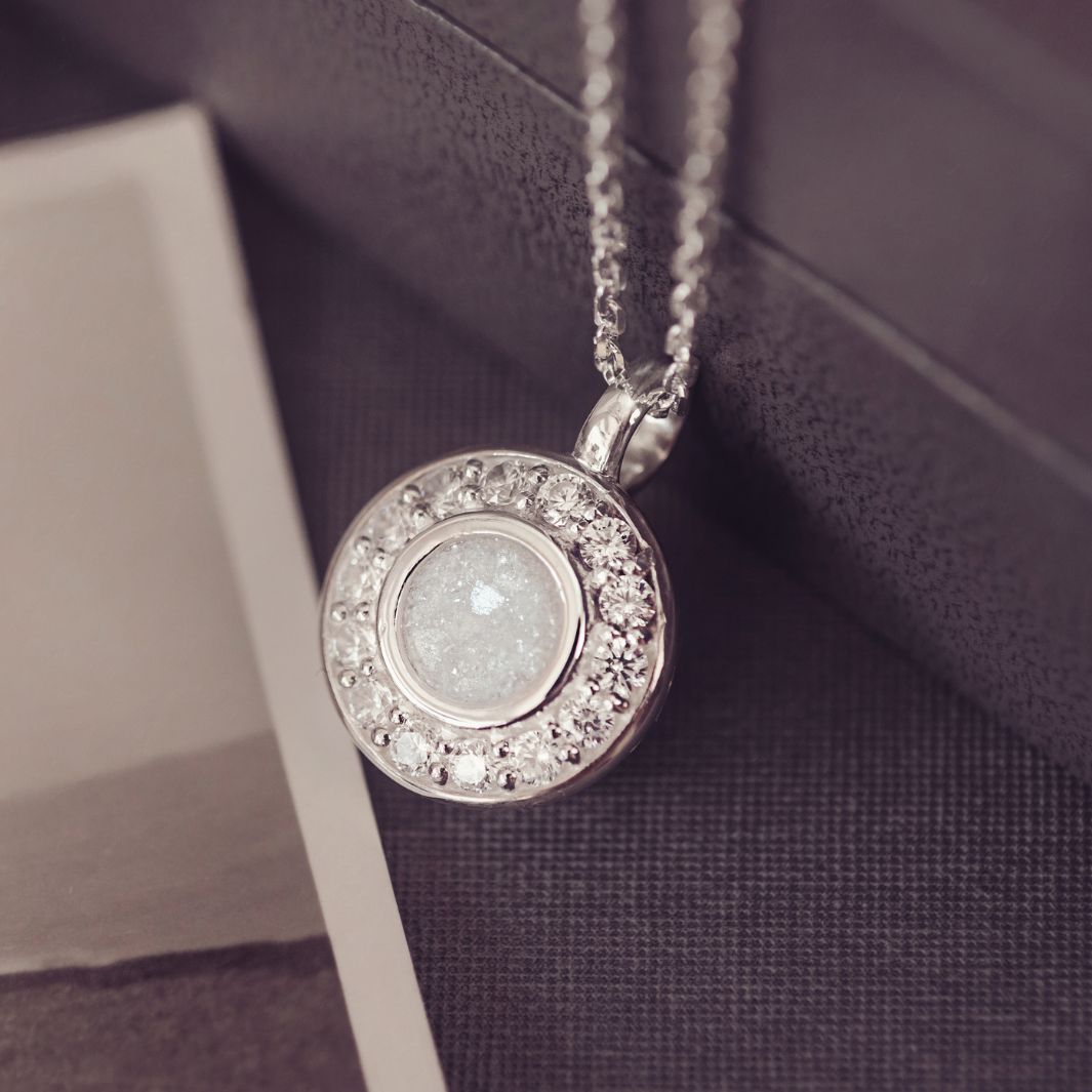 Silver necklace with a round pendant on a textured surface