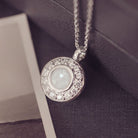 Silver necklace with a round pendant on a textured surface