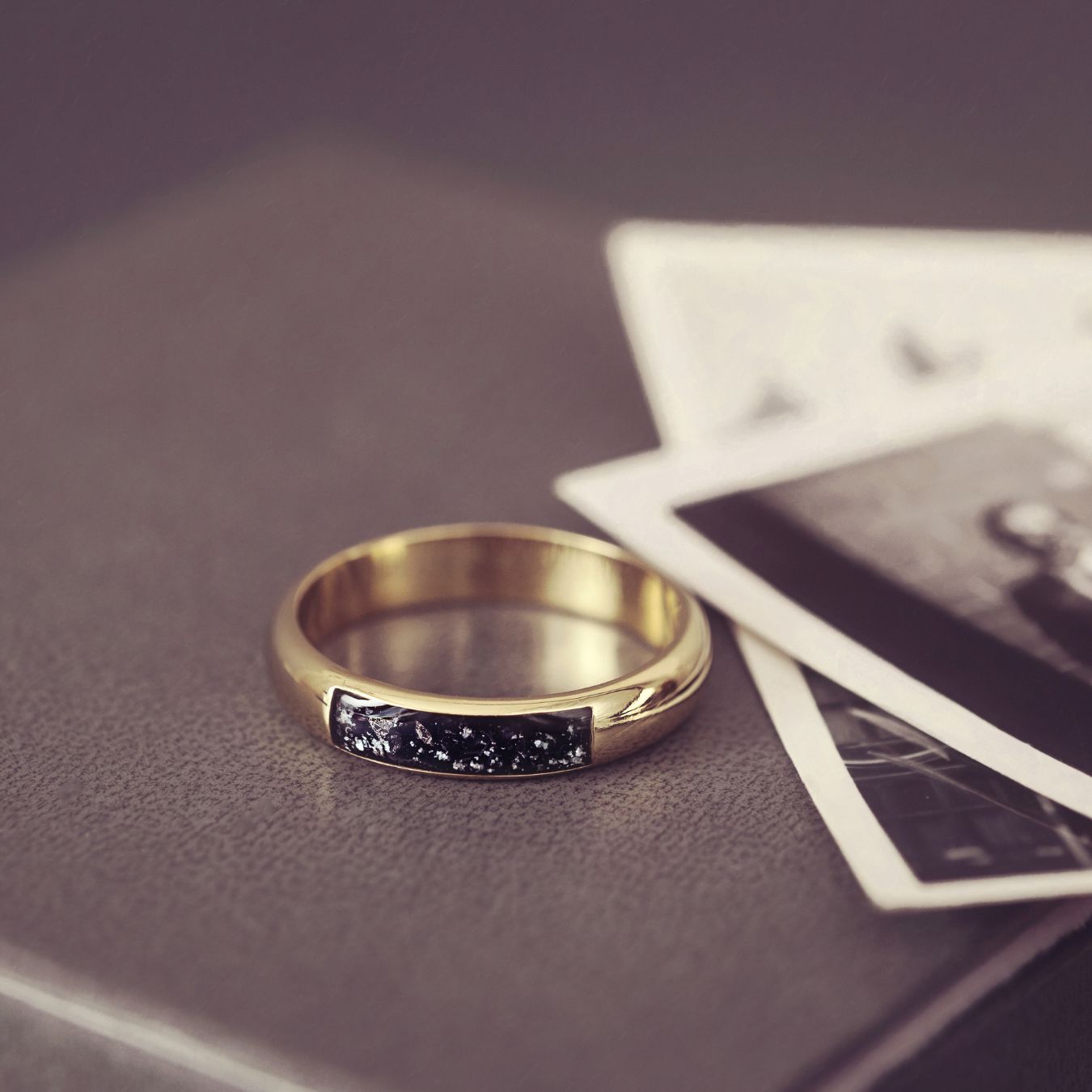 Gold ring with a black gemstone on a textured surface with playing cards.