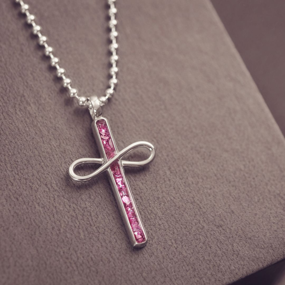 Necklace with a cross pendant featuring pink stones on a textured surface