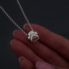 womans hands with pink nails demonstrating how to fill a silver paw ashes necklace. The necklace has "willow" engraved on the back. It shows her unscrewing the chamber and adding the ashes with a funnel. Its then displayed in a jewellery box.