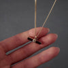 demonstration of a gold T-Bar self fill urn necklace. the video shows a womans hands with pink nails unscrewing the urn and using a funnel and stick to fill the urn necklace.