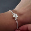 demonstration of a silver heart self fill urn charm. the video shows a womans hands with pink nails unscrewing the urn and using a funnel and stick to fill the urn necklace.