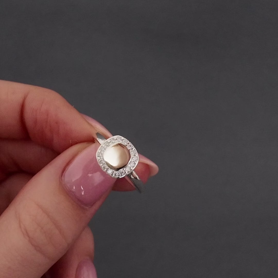 womens hand with pink nails showing a demonstration of filling a silver cluster ring with cremation ashes. she uses a screw driver to remove to screw to the chamber and funnels in the ashes. its then displayed in a grey jewellery box.