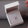 Silver ashes small round pendant necklace with purple crystals in a grey jewellery box held in a women's hand.