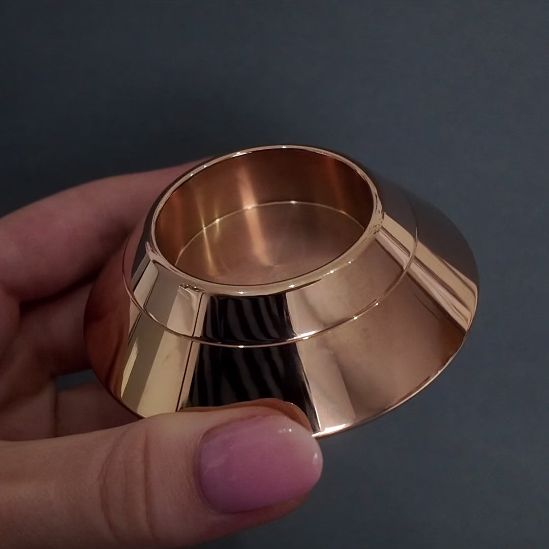 womans hands with pink nails demonstrating how to fill a rose gold candle urn with ashes against a dark grey background. 