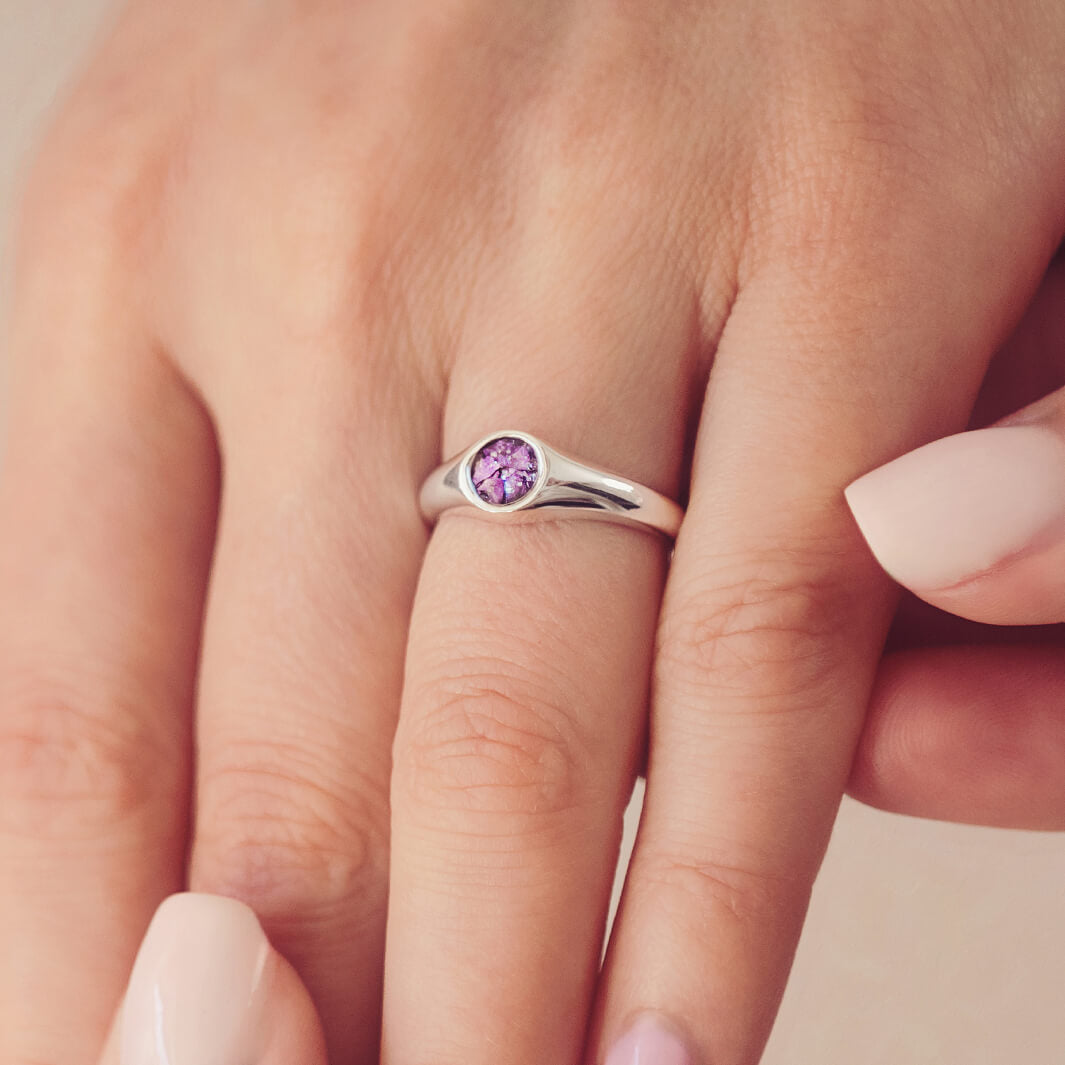 sterling silver ring band with circular stone holding cremation ashes and purple crystal